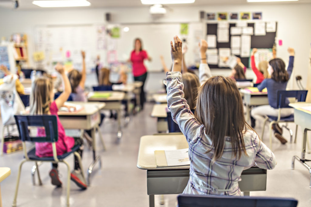 Classroom of young children raising hands